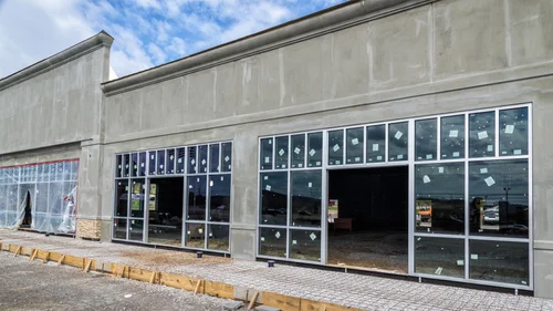 Storefront under construction with large windows and unfinished exterior, showcasing renovation progress for commercial space by OZ General Contracting.