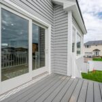 Modern home exterior with large windows, gray siding, and a deck, showcasing inviting outdoor space for springtime renovations.