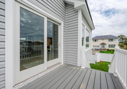 Modern home exterior with a porch, sliding glass doors, and landscaped yard, illustrating springtime renovation and landscaping themes.
