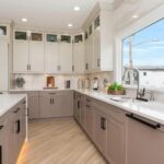 Modern kitchen interior with light-colored cabinets, quartz countertops, and large window, showcasing a stylish renovation by OZ General Contracting.