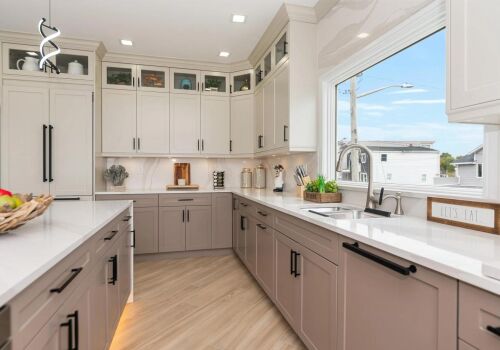 Modern open-concept kitchen design featuring light cabinetry, quartz countertops, and a bright window view, emphasizing home remodeling and improvement.
