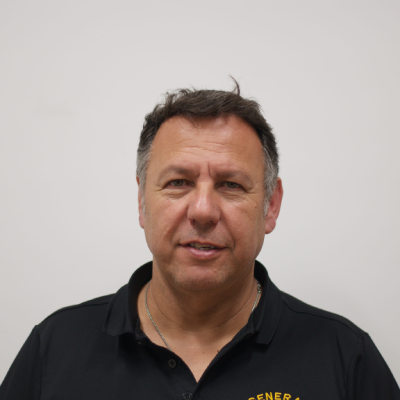 Mike Ovadia, Project Manager at OZ General Contracting, in a black polo shirt with company logo, smiling against a plain background.
