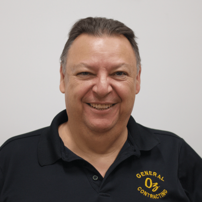 Uzi Ovadia, Owner and Founder of OZ General Contracting, smiling in a black polo shirt with "GENERAL CONTRACTING" logo, representing nearly 50 years of expertise in kitchen and bathroom remodeling on Long Island.