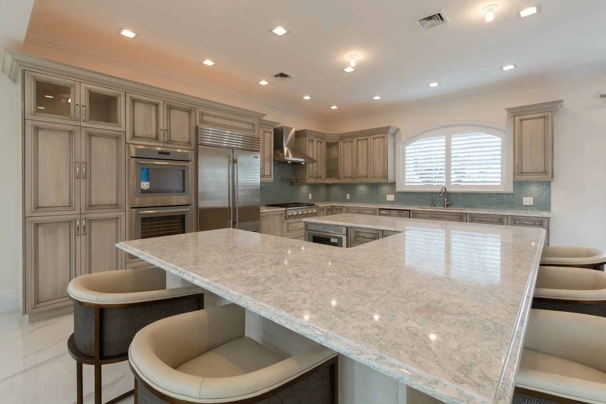 Modern kitchen with gray cabinetry, marble island, and stainless steel appliances.