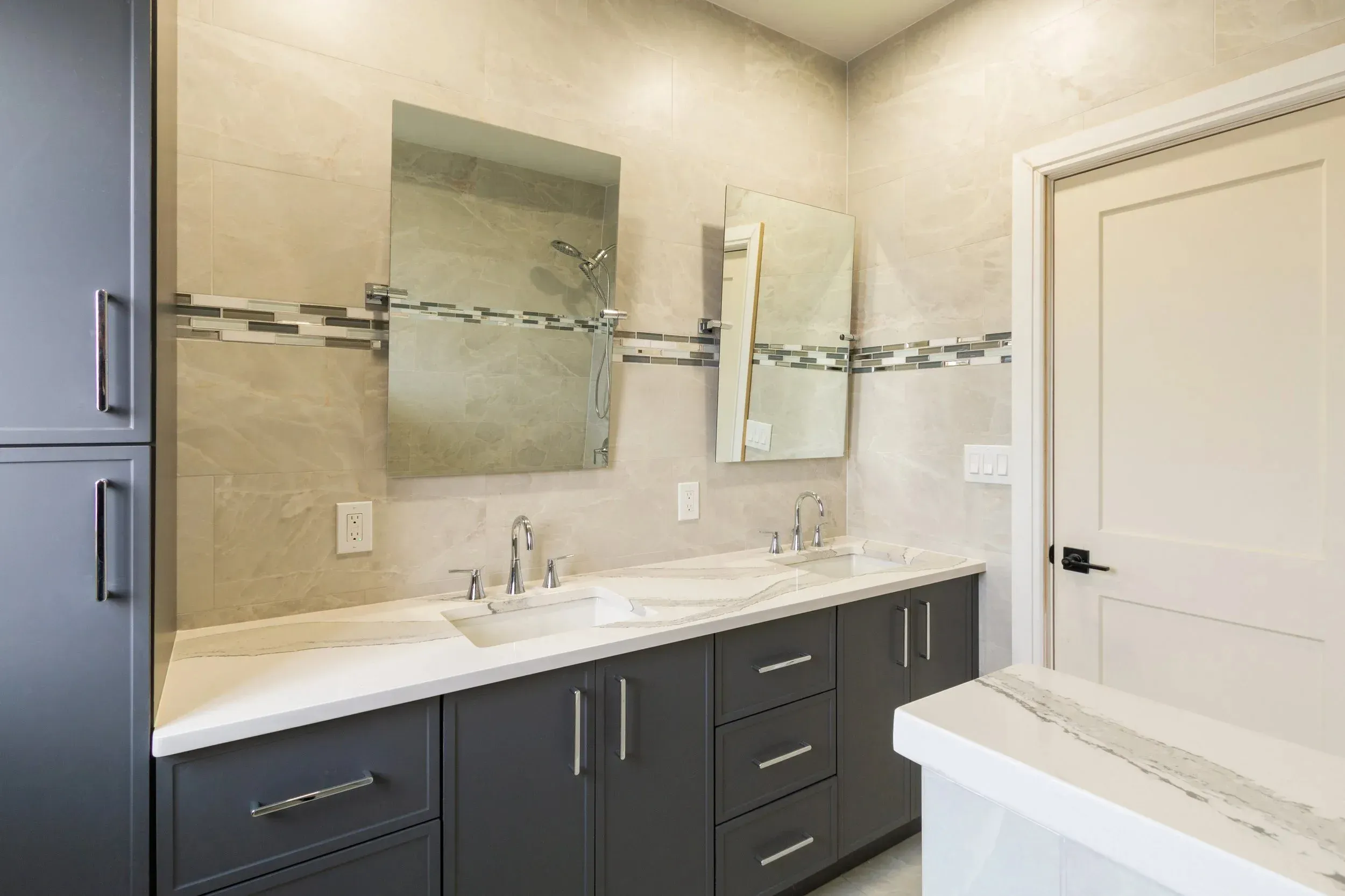 Modern bathroom with double sinks, large mirrors, and elegant tile accents.