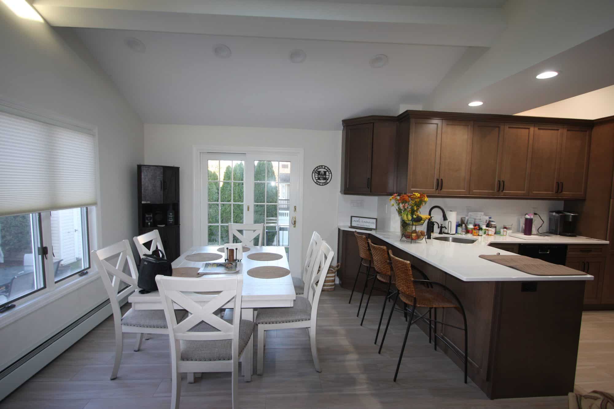 Wide view of the kitchen and dining area under a vaulted ceiling with recessed lights