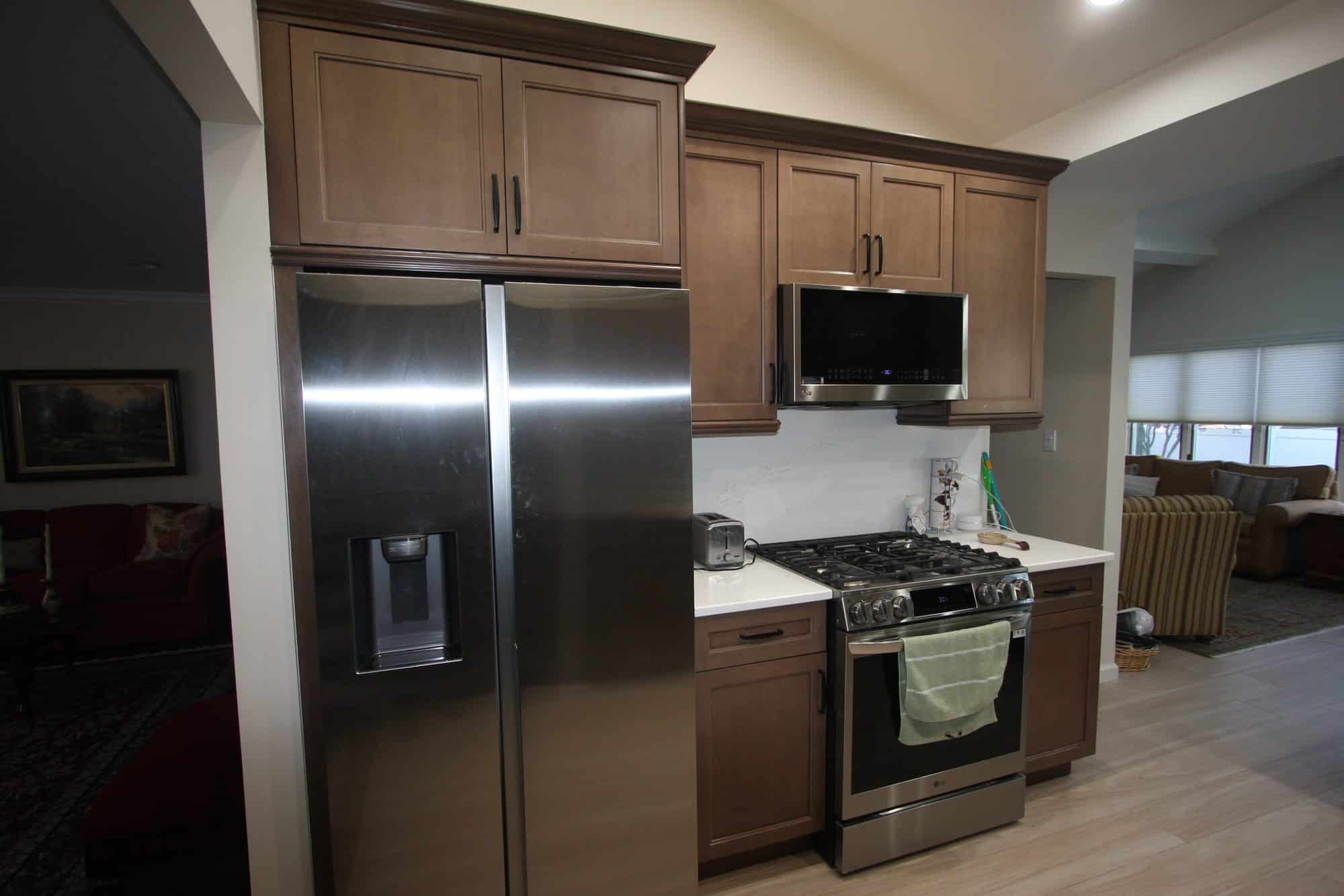 Stainless side-by-side refrigerator in a cabinet surround beside a stainless gas range and over-range microwave