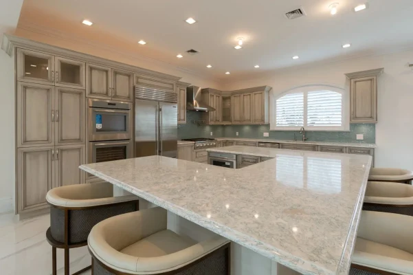 Modern kitchen with gray cabinetry, marble island, and stainless steel appliances.
