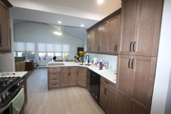 Remodeled Plainview kitchen with stained shaker cabinets, a tall pantry, white quartz counters and a vaulted ceiling opening into the family room
